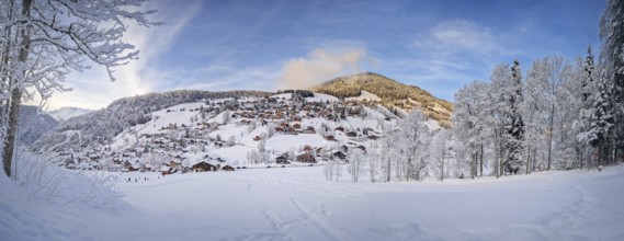 Panoramic winter scene of snow covered La Clusaz village nestled in a hilly landscape in Annecy,