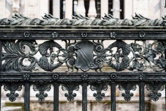 Antique wrought iron fence near the Duomo Cathedral in Milan with spikelets, shields, flowers and