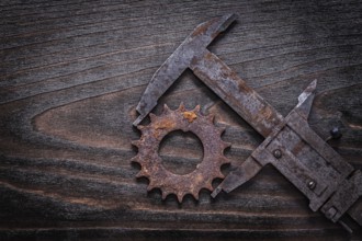 Rusty retro-styled measuring calipers with pinion gear on vintage dark wooden background