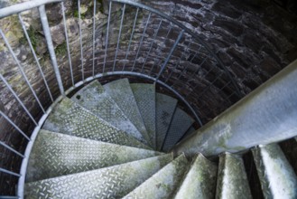 Steps of old metal spiral staircase disappear in darkness