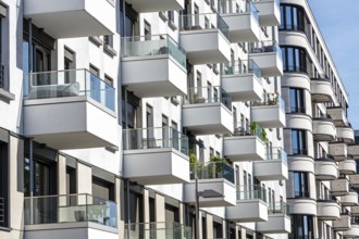 The façade of a white modern apartment block with many small balconies, seen in Berlin, Germany,