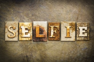 The word SELFIE written in rusty metal letterpress type on an old aged leather background