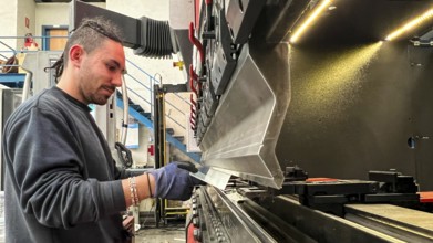 Young worker bending metals on a press brake. Metalworking industry
