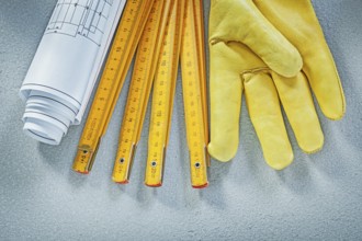Set of safety gloves construction drawings wooden meter on concrete background building concept