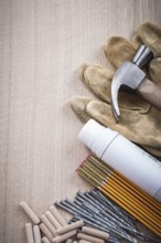 Wooden meter dowels construction plans claw hammer pair of safety gloves and nails on wood board