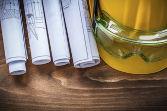 Goggles construction plans and hard hat on brown wood board