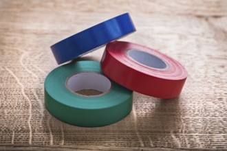 Three rolls of insulating tape on wooden board construction concept