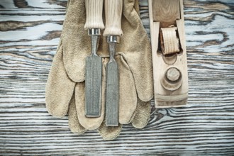 Protective gloves flat chisels planer on wooden board