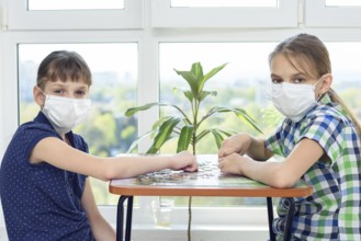 Two girlfriends in medical masks play puzzles and looked into the frame