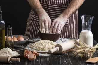A handful of flour with egg on a rustic kitchen. Against the background of men's hands knead the