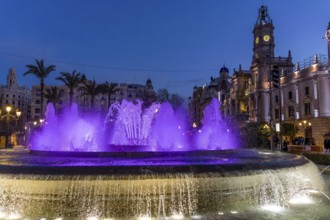 Night photo with purple illuminated water round fountain and blue sky in the centre of the old town