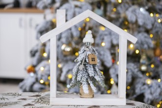 Key on Christmas tree and tiny house on cozy home with Christmas decor on table of festive white