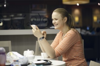 Young beautiful woman chatting on smartphone sitting in cafe