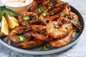 Grilled shrimps served with hot sauce and slices of fresh lemon, homemade, no people