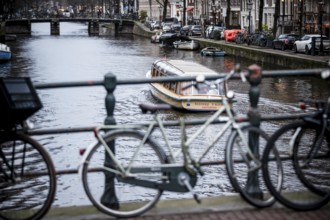 A canal tour boat navigates the web of canals in the central region of the city of Amsterdam, The