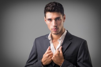 Young businessman confidently posing in front of camera, wearing business suit without neck-tie,