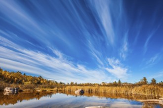 Cirrus clouds are reflected in the Winnipeg River. Wonderful autumn day. Old Pinawa Dam Park. The