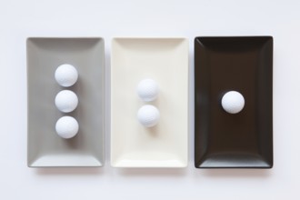 Different ceramic dishes with golf balls on over white background, rectangle dish