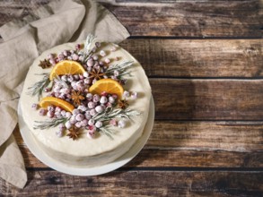Winter homemade cake on wooden background. White cream christmas cake decored rosemary,