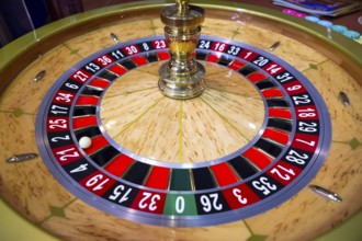 Roulette table in casino. Ball in the rotating gambling machine. Wooden roulette wheel
