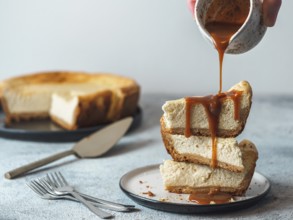 Caramel pouring on stack of three cheesekace pieces. Cheesecake with caramel on gray cement