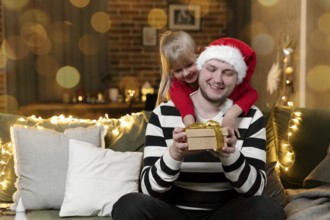 Merry Christmas and Happy New Year. Christmas gift surprise. A little smiling daughter girl hugging