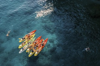 Tourists swim in the turquoise sea near a team of kayakers in kayaks. Drone., ????????