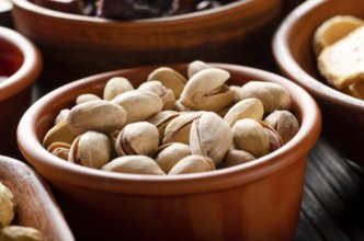 Pistachio nuts in clay bowl on kitchen wooden table food background