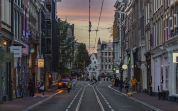 A picture of a street in Amsterdam at sunset