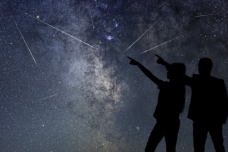 Silhouette of young couple watching Meteor Shower. Nigh Sky