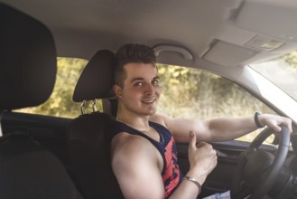 Portrait of smiling young man sitting in a car and looking at the camera on a sunny day