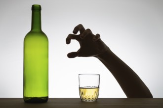Silhouette of a hand reaching for a glass of wine