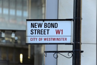White street sign with black and red lettering, urban environment, London, London region, England,