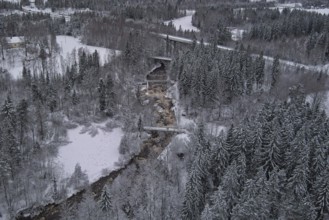 Aerial view of Myllykoski rapids on a cold winter day with snow covered ground and tree branches,