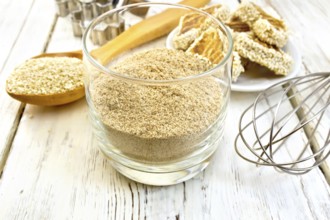 Sesame flour in a glass, a spoon with sesame seeds, cookie cutters and a mixer, biscuit on the