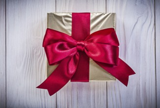 Giftbox in glittery paper with red bow on wood board holidays concept
