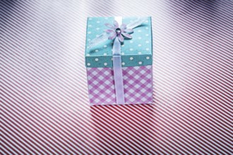 Gift box on striped fabric background top view celebrations concept