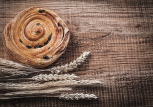Rich raisin bakery bunch of wheat ears on oak wooden board food and drink concept