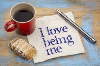 I love being me - positive affirmation - handwriting on napkin with a cup of coffee