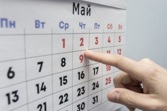 Hand points to the May 2 holiday on a wall calendar sheet