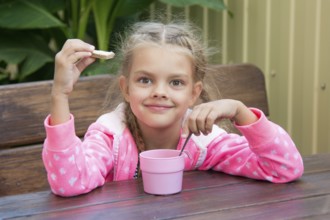 Girl sitting at a wooden table on the porch, and breakfast