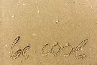 Be cool written on the beach. sand background