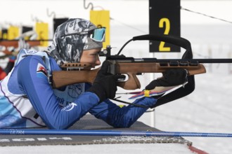 Sportswoman biathlete aiming, rifle shooting in prone position. Biathlete Arina Soldatova Kamchatka