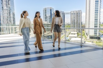 Three businesswomen are walking on a terrace of a tower building