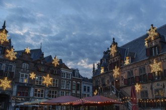 Historic buildings on a market with Christmas lights and cloudy sky at night, nijmegen, the