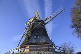 General view of a windmill with broad wings and blue sky, empty, east frisia, germany
