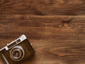 Wooden table background with old vintage camera. Flat lay or top view