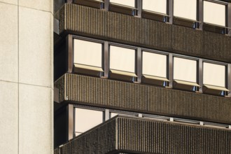 Sunlight illuminating a modernist building facade with ribbed concrete and rows of windows with