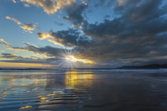 Sunrise over the ocean. Gentle cloud colors are reflected in the ocean water. Light wind causes