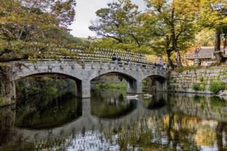 Gongju, South Korea. October 18, 2020: Footbridge over still river at Makoksa Temple on sunny day